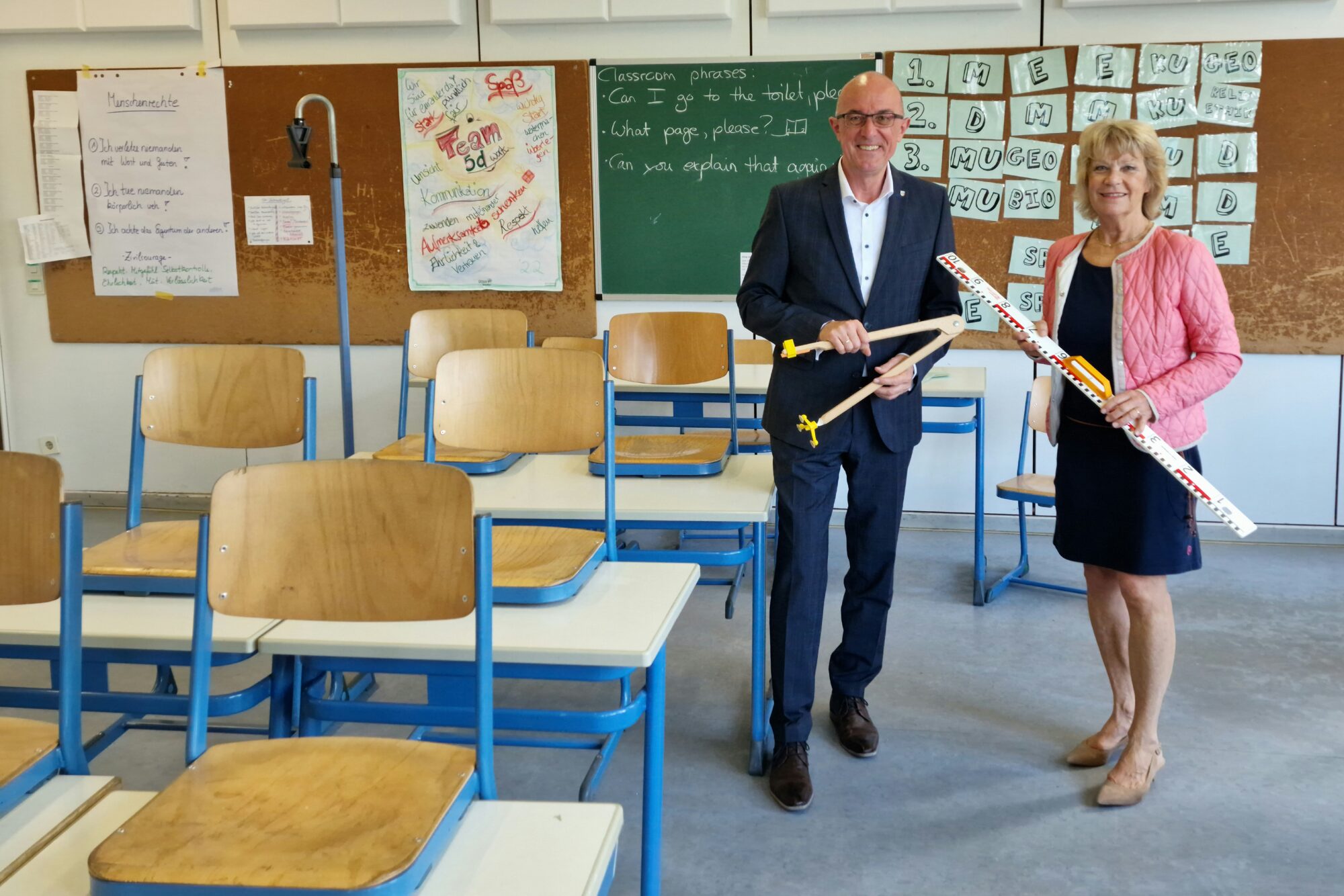 Links Landrat Dr. Klaus Metzger, rechts daneben die Vorsitzende der Humanitas Aichach. Beide stehen in einem Klassenzimmer der Realschule.