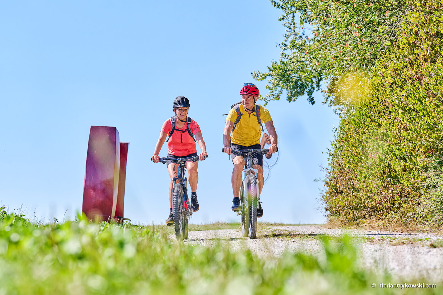 Eine Frau und ein Mann fahren mit Fahrradhelm auf einem Fahrrad