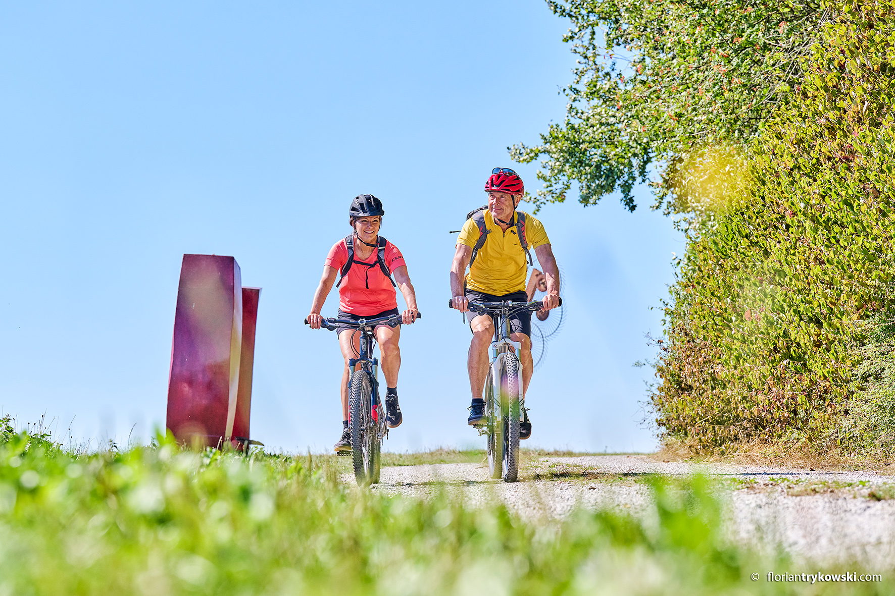 Eine Frau und ein Mann fahren mit Fahrradhelm auf einem Fahrrad