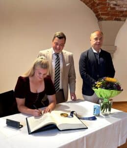 Dajana Eitberger aus Aindling Weltmeisterin und Olympiasiegerin im Rennrodeln, trägt sich ins Goldene Buch des Landkreises ein. Neben ihr stehen Landrat Dr. Marc Sturm und BLSV-Kreisvorsitzender Richard Hangl.